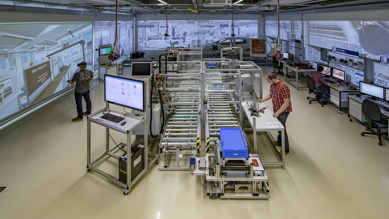Produktionshalle mit drei Arbeitern in einer digitalen Umgebung